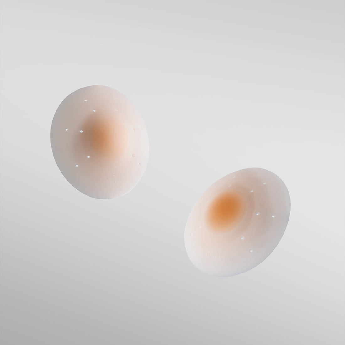 Pair of Essential silicone petals in fair shade on white background with breathe points and adhesive-free center.