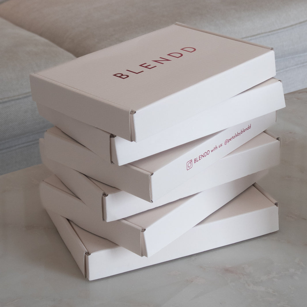 Stack of white BLENDD product boxes with branded packaging