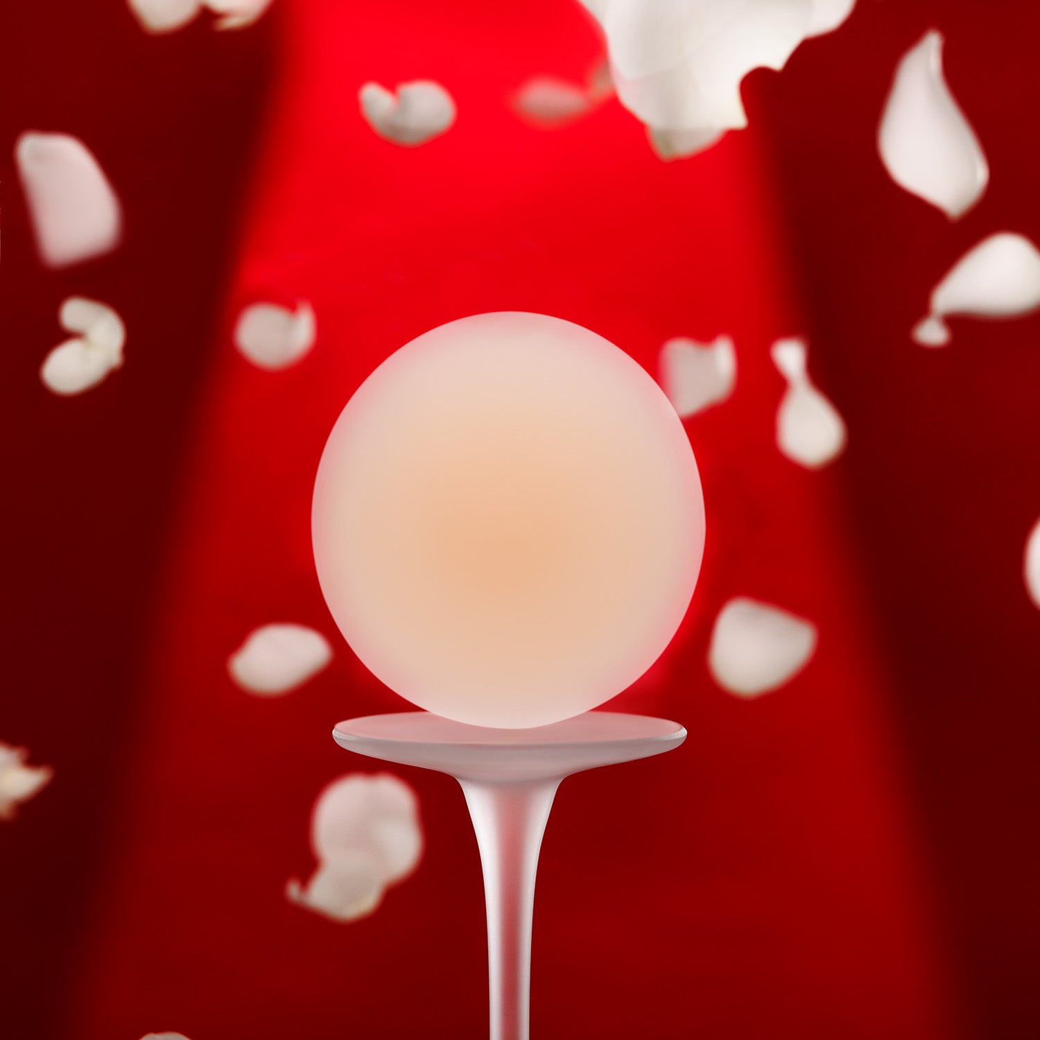 Naturelle silicone petal on white platform with falling petals, red background, and spotlight lighting.