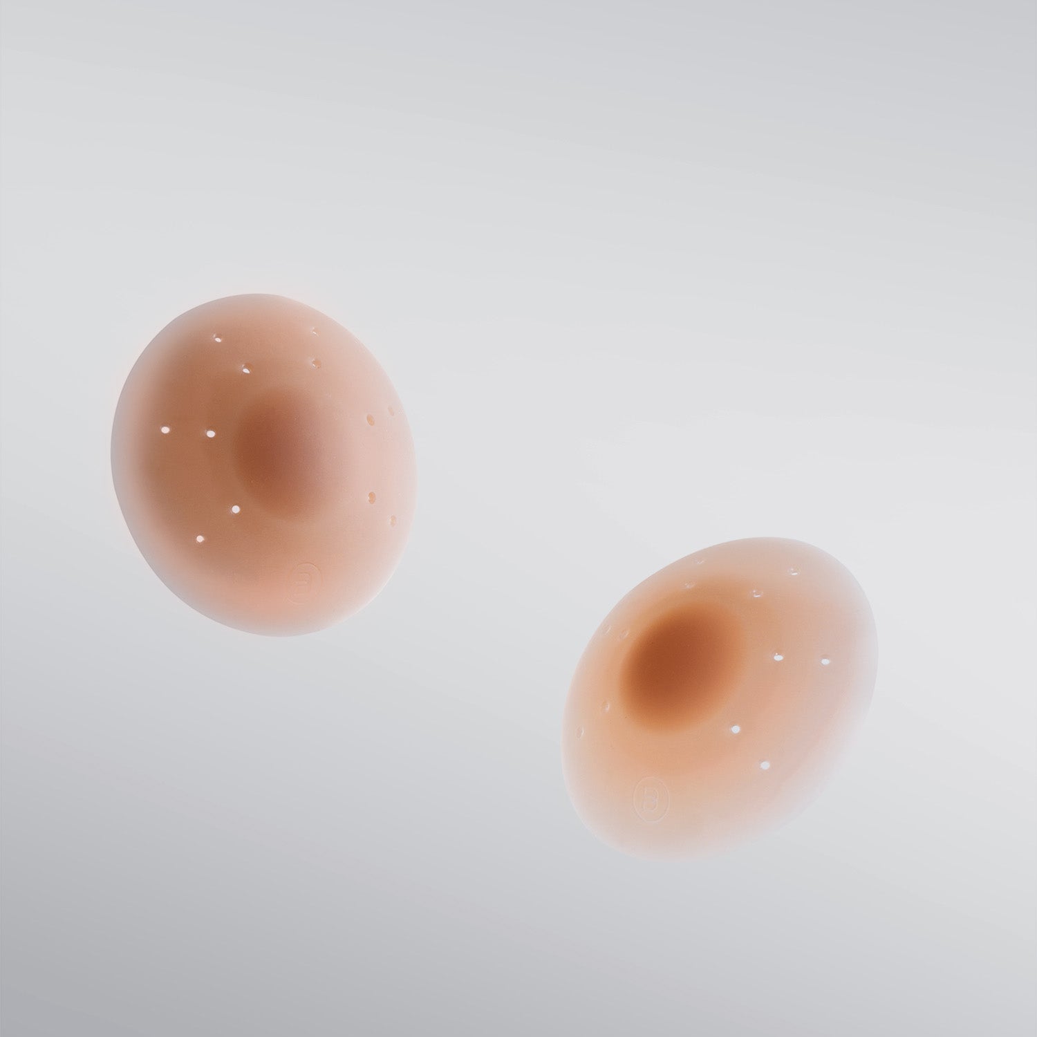 Pair of Essential silicone petals in tan shade on white background with breathe points and adhesive-free center.