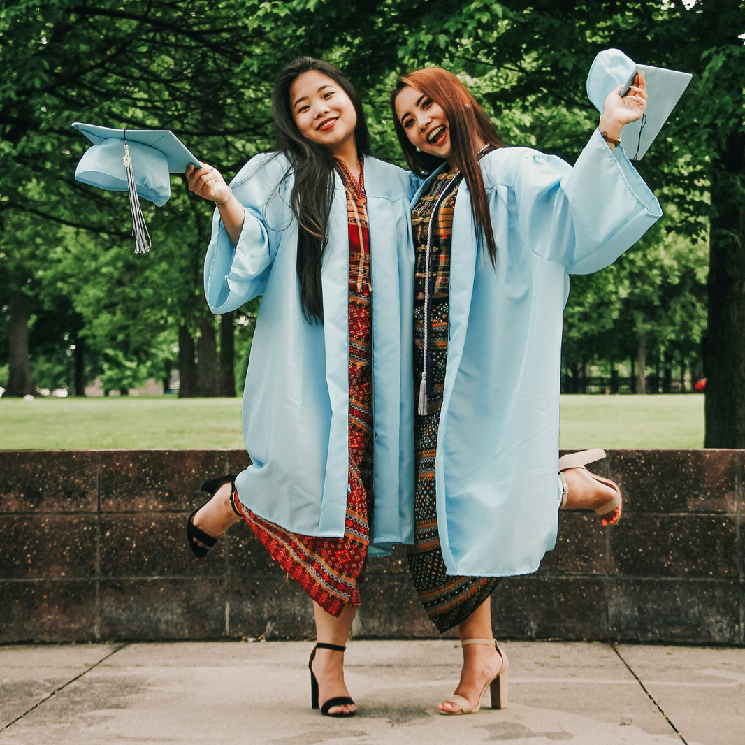 Two young women in graduation caps celebrating academic achievement outdoors